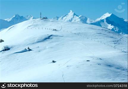 Cross on winter mountain Shneeberg top and view Alps peaks behind (Hochkoenig region, Austria)