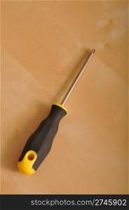 cross screwdriver with plastic handler on a brown wooden background
