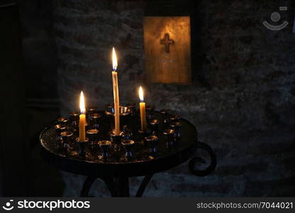 cross sign and and candles over dark background in a church