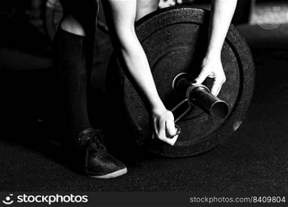 Cross training. Female athlete changing weights on barbells