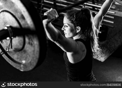 Cross training. Female athlete lifting heavy barbells