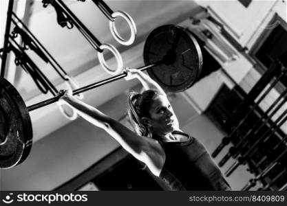 Cross training. Female athlete lifting heavy barbells