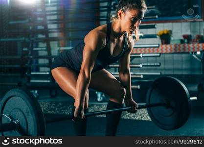Cross training. Female athlete lifting heavy barbells