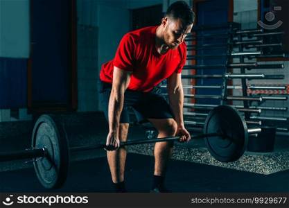 Cross training. Male athlete lifting heavy barbells