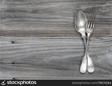 Crossed vintage fork and spoon on old wooden boards