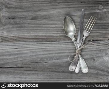 Crossed vintage fork, table knife and spoon on old wooden boards