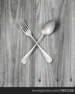 Crossed vintage forks and spoons on old wooden boards
