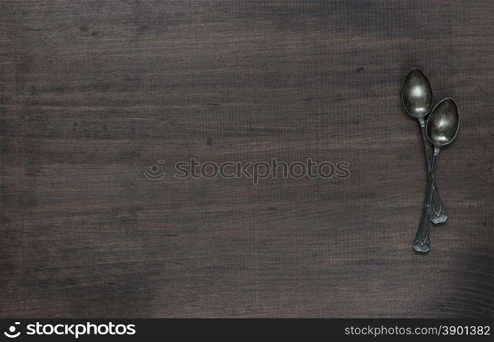 Crossed vintage spoons on the old dark wooden board