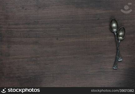 Crossed vintage spoons on the old dark wooden board