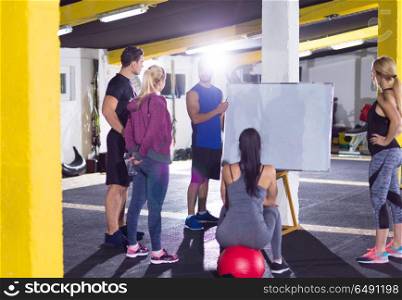 Crossfit training course.group of young athletes getting instructions from trainer before exercise at crossfitness gym. athletes getting instructions from trainer