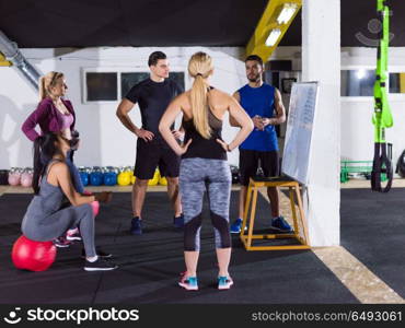 Crossfit training course.group of young athletes getting instructions from trainer before exercise at crossfitness gym. athletes getting instructions from trainer