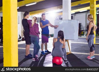 Crossfit training course.group of young athletes getting instructions from trainer before exercise at crossfitness gym. athletes getting instructions from trainer