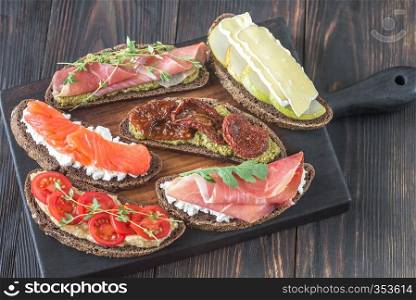 Crostini with different toppings on the wooden board