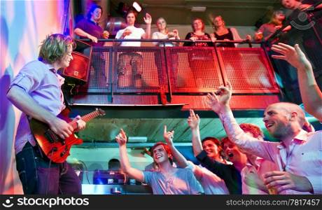 Crowd going wild during a live performance of a guitarist in a club