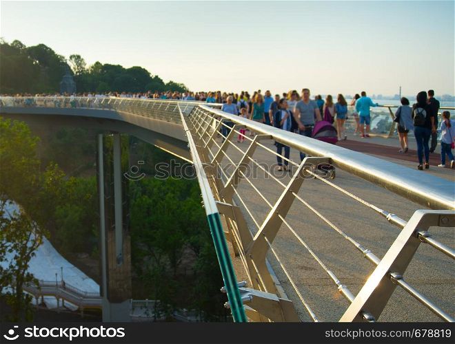 Crowd of people at new Pedestrian-Bicycle Bridge at sunset. Focus in the foreground