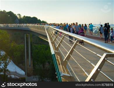 Crowd of people at new Pedestrian-Bicycle Bridge at sunset. Focus in the foreground