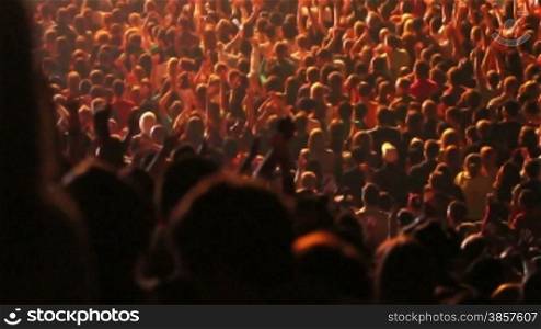 Crowd of people raising their hands and applauding at a concert
