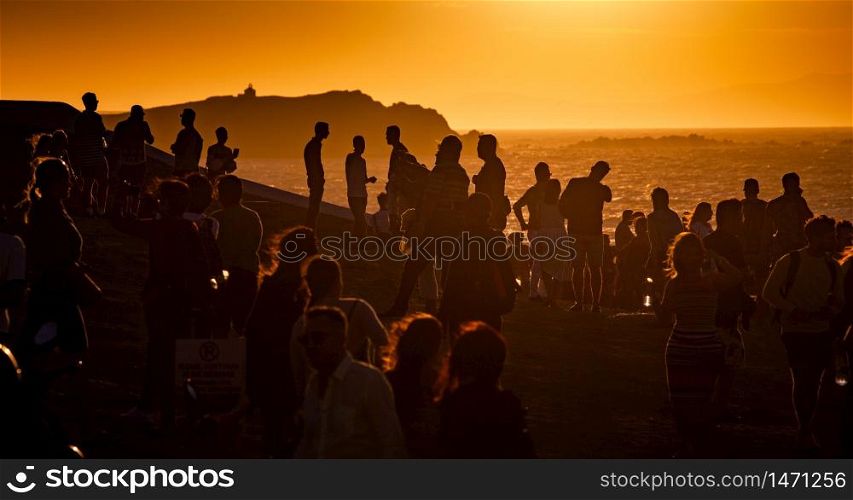 crowd of people watching sunset by the sea