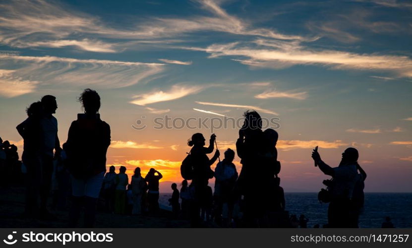 crowd of people watching sunset by the sea