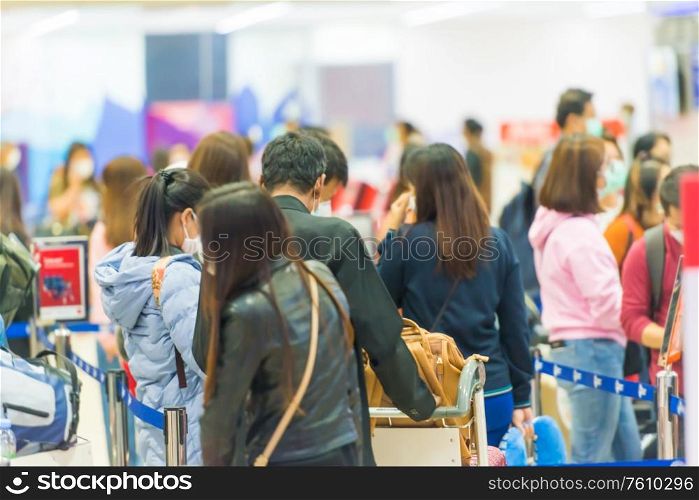 Crowd of people with luggage waiting in line in airport during coronavirus quarantine