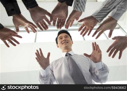Crowd Reaching for Businessman