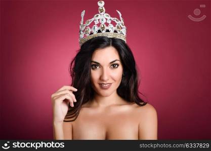 Crowned woman like miss of beauty looking at camera isolated on red wine background. Girl wearing crown, studio shot.
