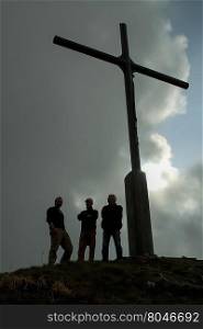 Crucifix on the top of mount Folgorito. Three pilgrims under Crucifix on the top of the mount Folgorito.