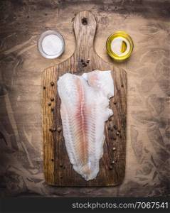 crude Pangasius on a cutting board with butter and salt on wooden rustic background top view close up