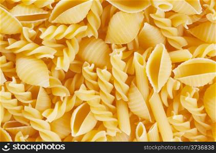 Crude tasty pasta of different shapes mixed on the table