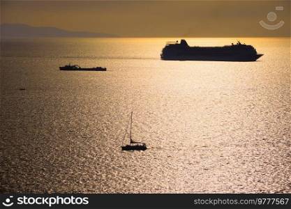 Cruise ship and yacht boat silhouettes in Aegean sea on sunset. Mykonos island, Greece. Cruise ship silhouette in Aegean sea on sunset