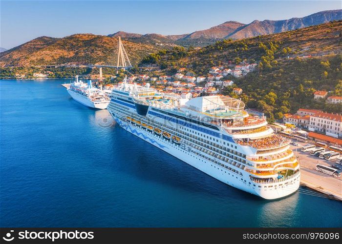 Cruise ship at harbor. Aerial view of beautiful large ships and boats at sunrise. Landscape with boats in harbour, city, mountains, blue sea. Top view of yacht. Luxury cruise. Floating liner in port