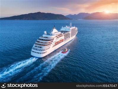 Cruise ship at harbor. Aerial view of beautiful large white ship at sunset. Colorful landscape with boats in marina bay, sea, colorful sky. Top view from drone of yacht. Luxury cruise. Floating liner. Aerial view of beautiful large white ship at sunset