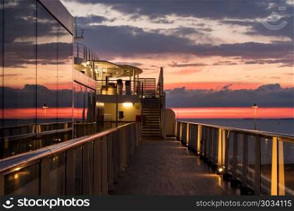 Cruise ship deck at sunset. Reflections of the sunset in the windows of a modern cruise ship at dusk. Cruise ship deck at sunset