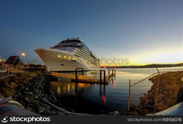 cruise ship moored in port of a city at sunset