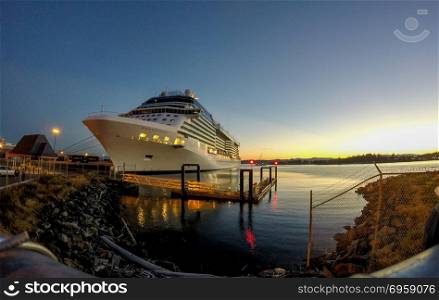 cruise ship moored in port of a city at sunset