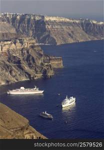Cruise ships moored below the cliffs in the volcanic caldera near the town of Imerovigli on the island of Santorini in the Aegean Sea off the coast of mainland Greece.