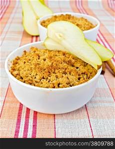 Crumble with pears in two white bowls, pear, cinnamon on linen tablecloth background