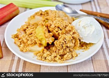 Crumble with rhubarb and ice cream in a white plate, stalks of rhubarb, cinnamon on a background of brown linen tablecloths