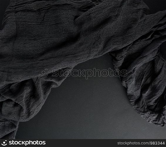 crumpled black gauze fabric on a black background, copys pace, top view