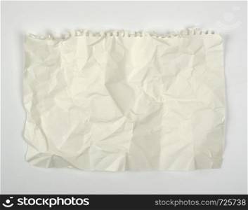 crumpled blank white rectangular sheet of paper torn out of a spiral notebook on a white background, copy space