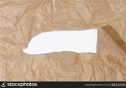 Crumpled brown paper with a torn hole