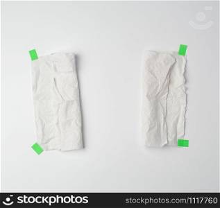crumpled dirty white piece of paper towel glued with green paper velcro on a white background, place for text