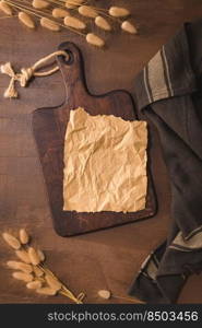 Crumpled paper and wooden cutting board on brown moody and rustic kitchen countertop.