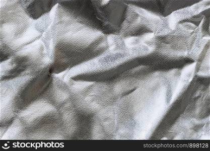 Crumpled silver metallized fabric with regular pattern. Background, texture
