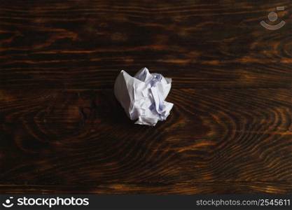 Crumpled up paper on brown wooden background. a Crumpled up paper on wooden background