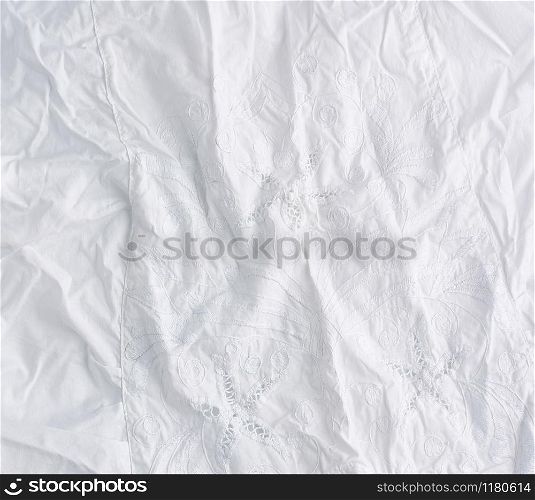 crumpled white cotton fabric with embroidery elements, fabric for sewing clothes and shirts, full frame