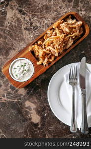 Crunchy deep fried calamari with Tartar sauce in hard wood plate on marble table, close up topview shot