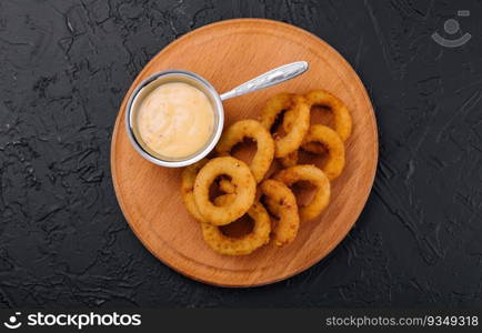 crunchy fried onion rings and sauce on wooden dish