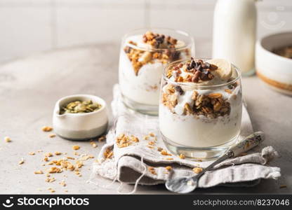 Crunchy granola with yogurt, banana, nuts, chocolate and honey in a glass on white background. Healthy breakfast concept.. Crunchy honey granola