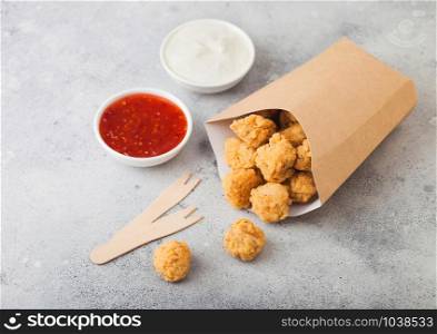 Crunchy southern chicken popcorn bites in paper container for fast food meals on light background.